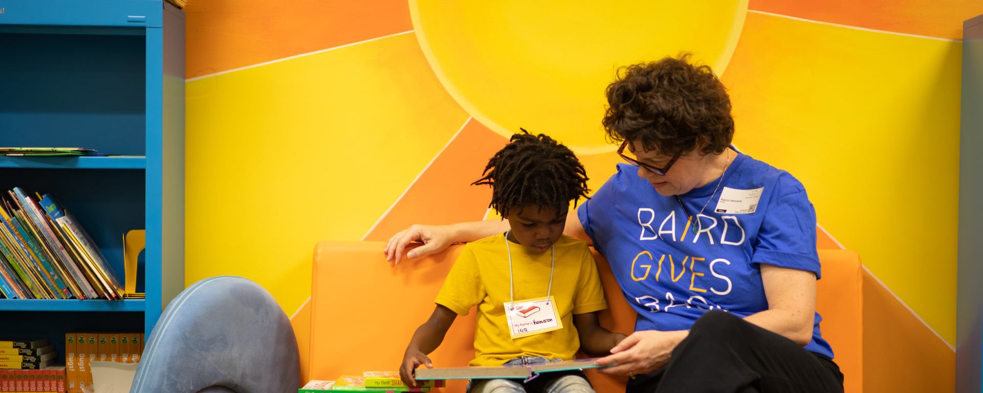 Woman in a Liberty Cares t-shirt reading to a student.