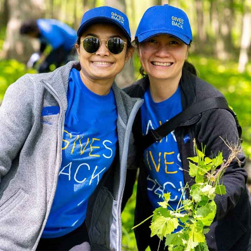 Two Liberty associates volunteering outdoors during in Liberty Gives Back apparel
