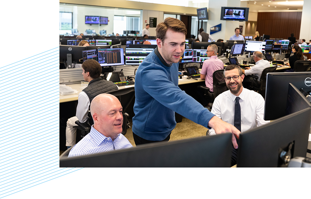 Three Liberty associates looking at computer monitors on the trading floor